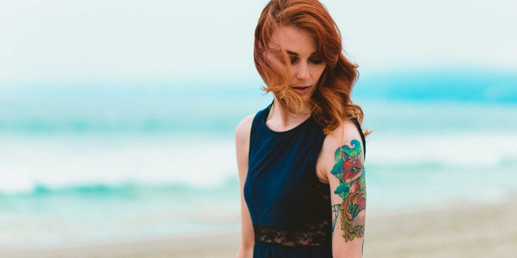 woman on beach with tattoo ink on left arm